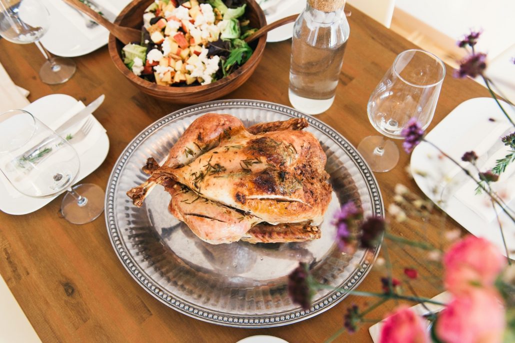 a thanksgiving holiday dinner of a roasted turkey on a silver platter with dishes on a table around it, very dissimilar to the pilgrims thanksgiving