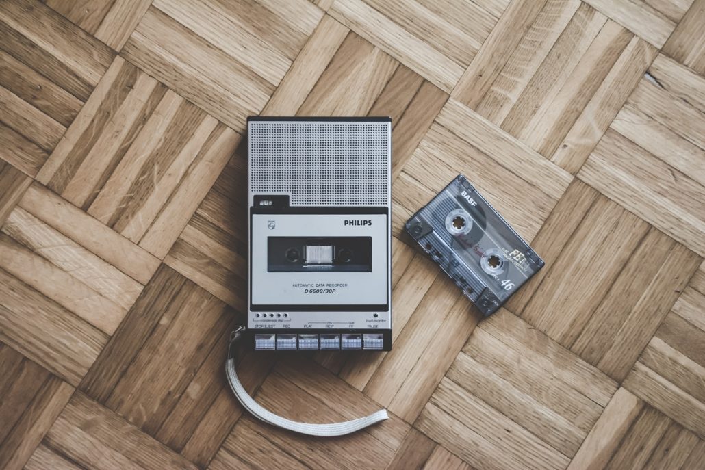 photo of a 1990's cassette player and a cassette tape on a parquet floor