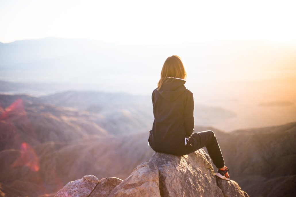 woman sitting on top of a mountain at dusk