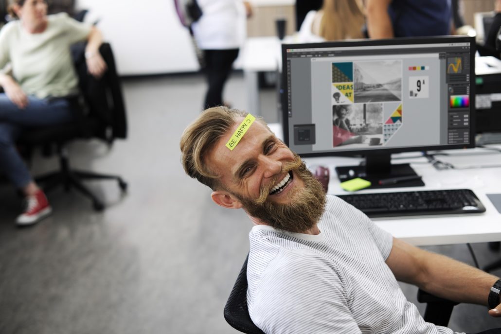Man laughing in an office showing the benefits of Sullivan's idea of free days being essential for productivity and happiness 