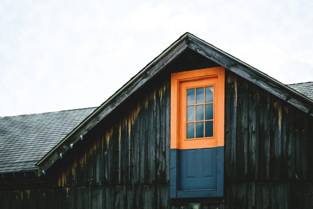 Dark wooden house with a blue and orange window. We get many questions about what goes into an appraisal inspection.