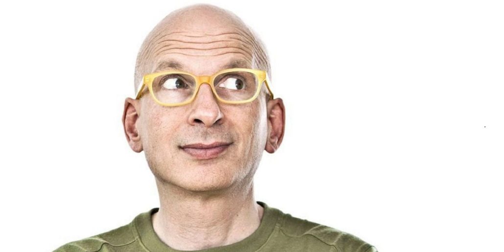 close up of Seth Godin wearing a green shirt and yellow glasses, a popular author and podcaster with young people