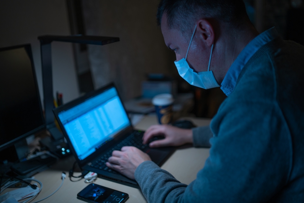 Man wearing respiratory mask looks up interest rates from home on a laptop during the Bay Area shutdown due to the Shelter in Place order to prevent the spread of COVID-19. 