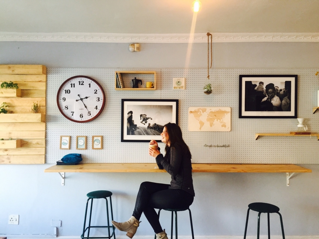 local young woman sitting at cafe counter drinking coffee and laughing