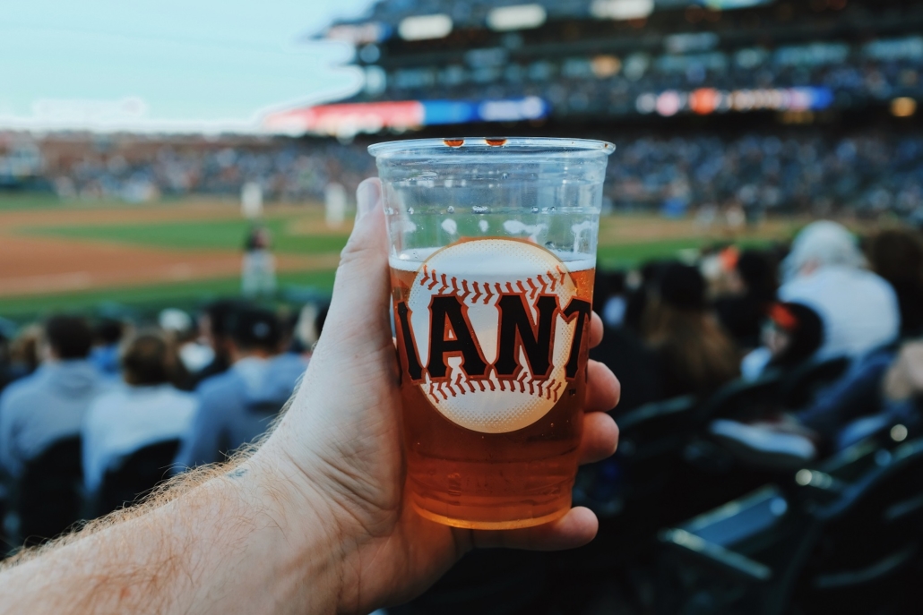 Baseball fan holds a beer in the baseball stadium during a game.