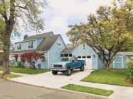 a blue house in the suburbs with a blue tuck parked inthe driveway and trees on either side of the home with a lawn