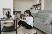 Woman sitting on the floor of her living room writing in a journal