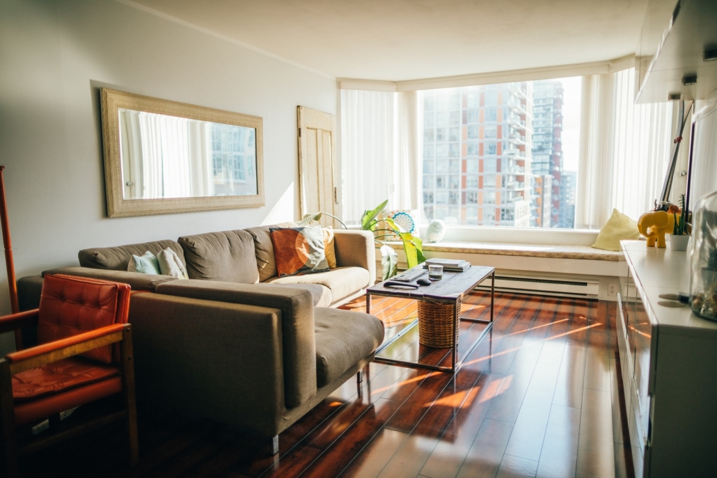 Condo living room with windows that feature a view of a city skyline. Condos are not necessarily cheaper than single-family homes. 