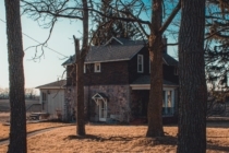 a large two story stone and wood house is surrounded by a yard of dry grass and trees located in a fire area, making it more likely to have additional appraisals or inspection requirements