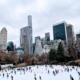 People ice skating in a public ice rink in the city surrounded by high-rise buildings with apartments that homebuyers purchased with low rates.