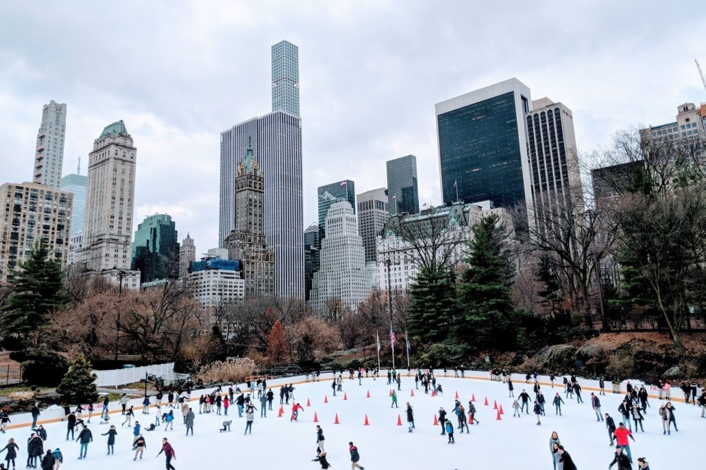 People ice skating in a public ice rink in the city surrounded by high-rise buildings with apartments that homebuyers purchased with low rates.