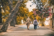 An elderly couple walks down the street together in a neighborhood. Elderly homeowners are staying in their homes rather than selling, which increases demand for housing during COVID. However, there are no signs of a housing bubble coming.