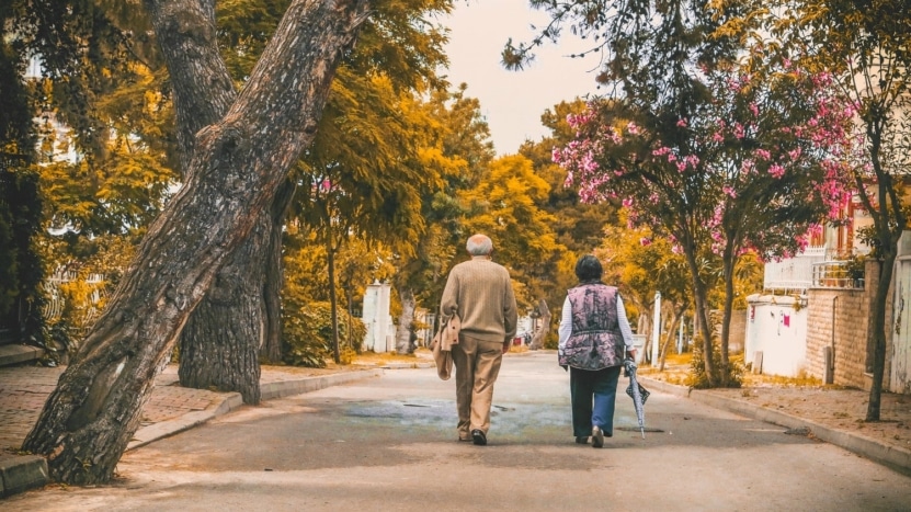 An elderly couple walks down the street together in a neighborhood. Elderly homeowners are staying in their homes rather than selling, which increases demand for housing during COVID. However, there are no signs of a housing bubble coming.