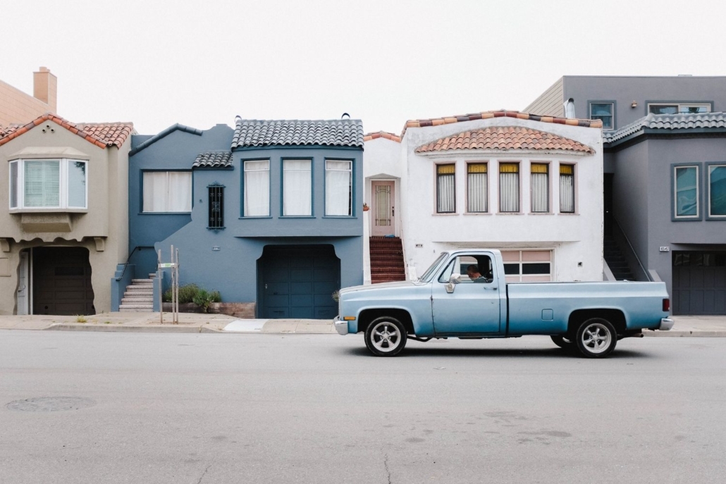 blue pickup truck is parked along the curb of a street in front of four homes, each with a with mortgage, located in the Sunset District of San Francisco 