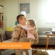 A veteran soldier in uniform plays with his young daughter in the living room of a home he purchased with no VA loan limit.