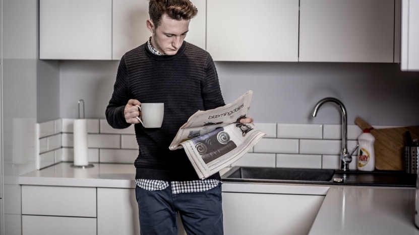 A young man reads a newspaper in his kitchen with a cup of coffee in hand. Consumers of information should be wary of experts - because they can be wrong, and are often.