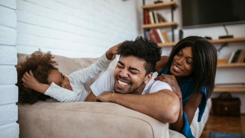 Family of three relax on couch, laughing