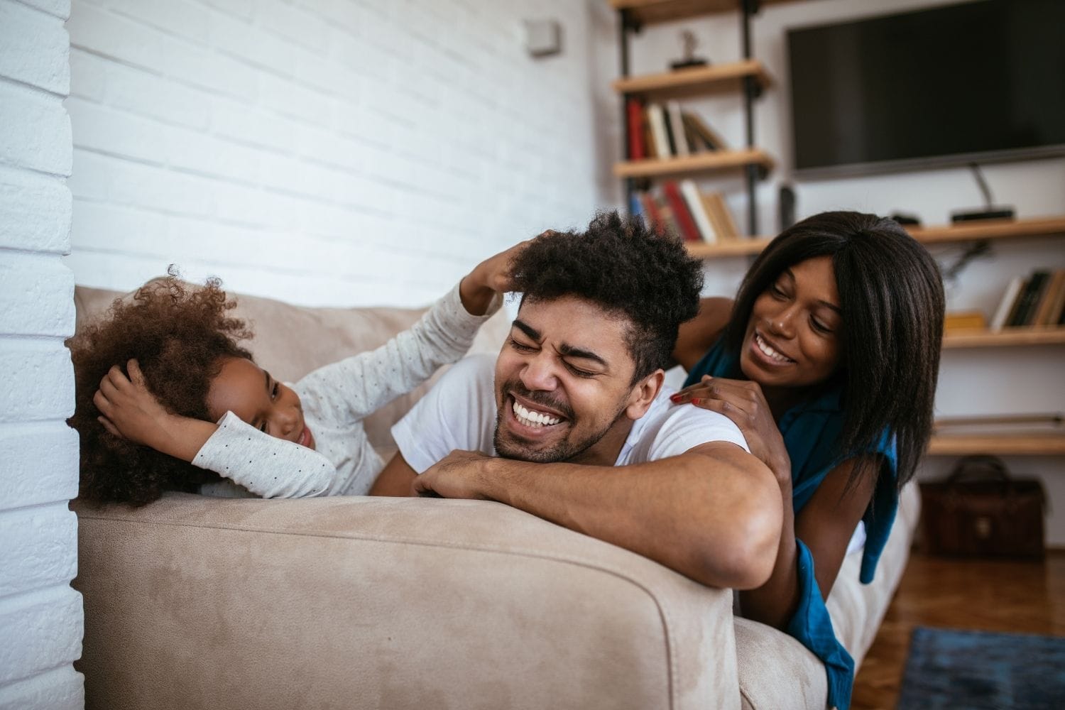 Family of three relax on couch, laughing