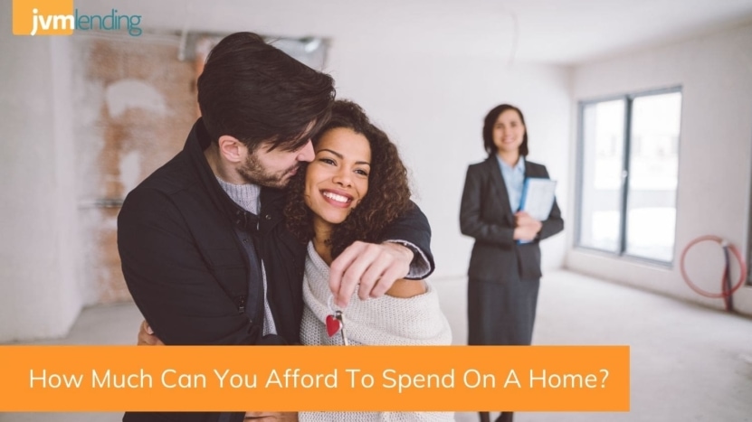 A young couples smiles while holding the keys to a new home with their real estate agent. After careful planning, they found out how much they could afford to spend on a home and purchased their first home.
