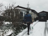 A man walks to his house in the winter carrying groceries. He purchased his home using points and potentially wasted his money.