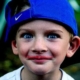 A young boy with a backwards blue Nike hat smiles for the camera with a Kool-Aid smile