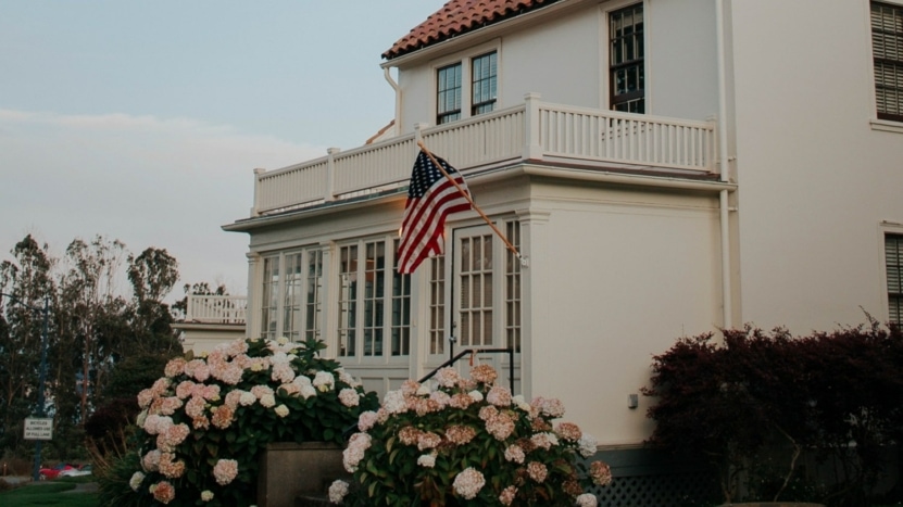 A white house with a terracotta roof sports an American flag hung by a first-time veteran homebuyer.