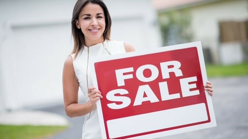 Real estate agent holding a FOR SALE sign