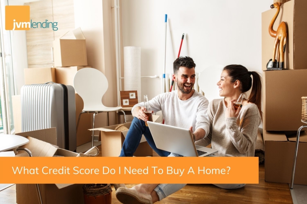 A couple sits on the floor of their new home looking at a computer to learn more about their credit score