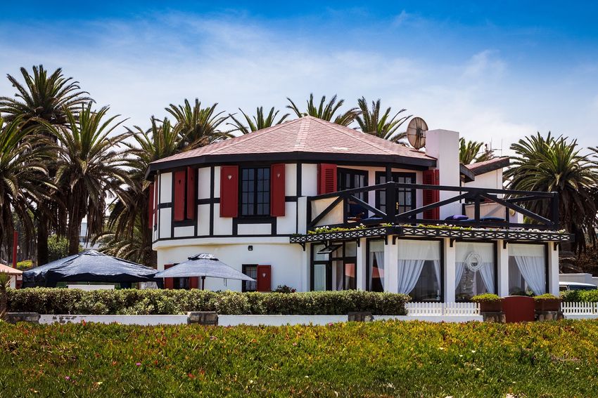 A white coastal second home with red and black accents is owner-occupied by the residents in order to receive more favorable funding.