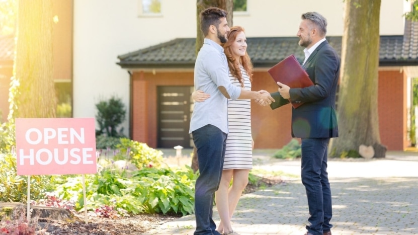 A young couple with a real estate agent tour an open house.
