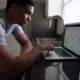 A young man looks at his laptop computer in the kitchen as he considers how to best diversify his assets to protect against inflation and deflation.