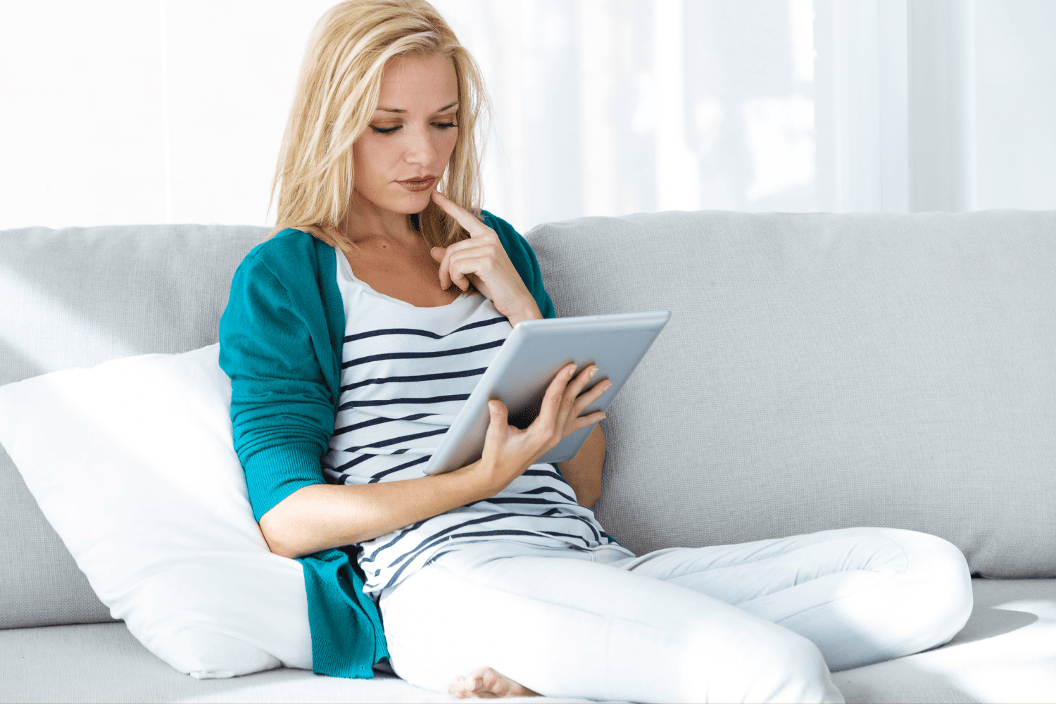 Woman sits on couch looking at tablet