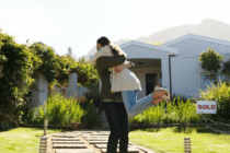 Couple hugging in front of sold home