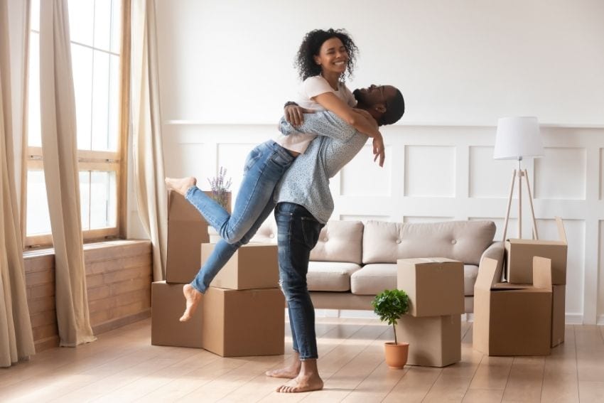 Couple celebrating in new home with moving boxes around them