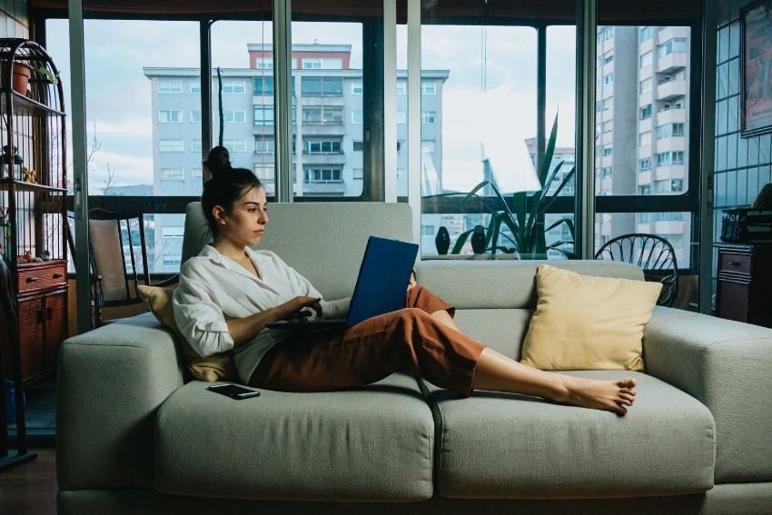 Woman working on laptop on the couch in her apartment