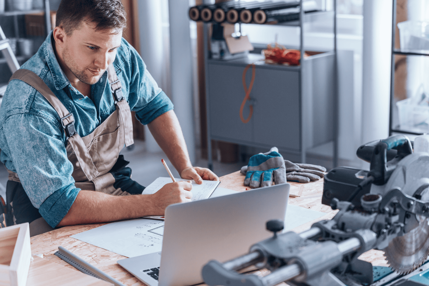 Self-employed man in overalls looking at laptop