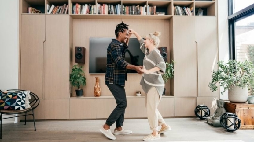 Biracial lesbian couple dance in their living room
