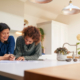 Female couple sign documents in kitchen