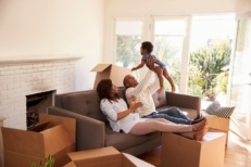 Family of three sitting on couch in new home with moving boxes