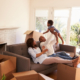 Family of three sitting on couch in new home with moving boxes