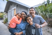 Portrait of happy family against house. Multi-ethnic parents and children are smiling on driveway. They are having fun together during weekend.