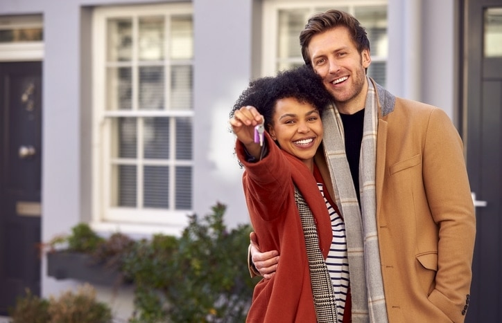 Portrait Of Multi Cultural Couple Outdoors On Moving Day Holding Keys To New Home In Fall Or Winter