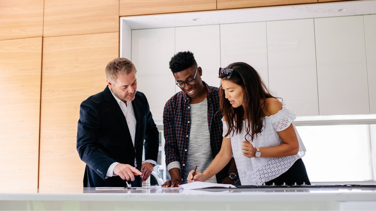 Couple talking to their realtor and signing on a piece of paper