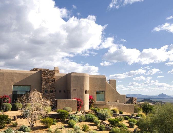Large home located on mountain butte overlooking desert landscape near Scottsdale, assuming a homebuyer is running different options on the Arizona mortgage calculator.