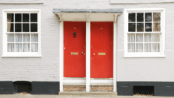 Two red front doors side by side on older building