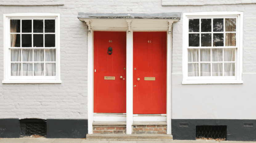 Two red front doors side by side on older building