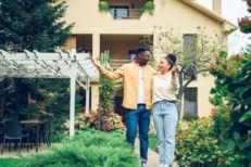 Happy young couple in front of new home they purchased.