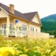 Small home set in rolling hills next to field of yellow flowers