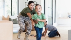 A mom US soldier chases an elementary age son through the house. Everybody is smiling and happy.