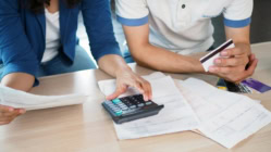 Two people sitting at a table with a calculator and credit card